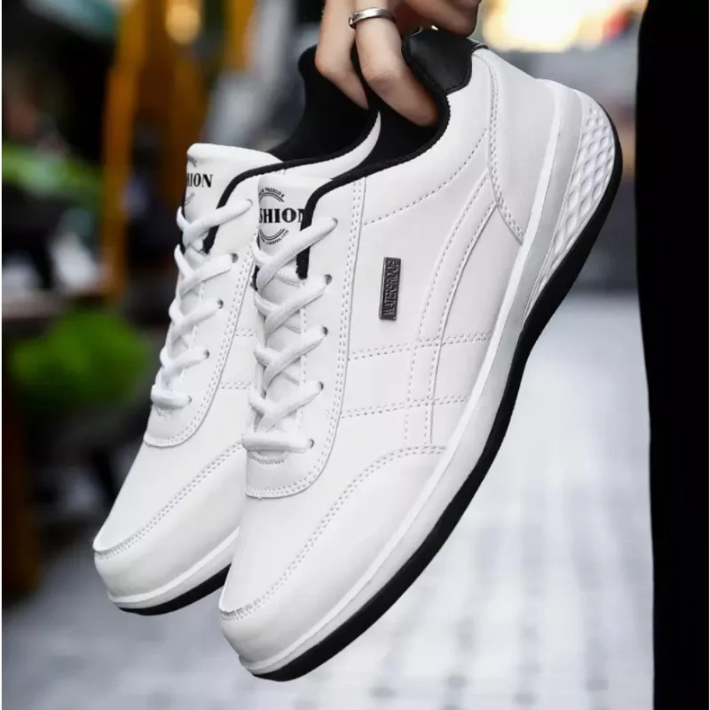 Navy trainer with tan accents shown mid-step on urban pavement