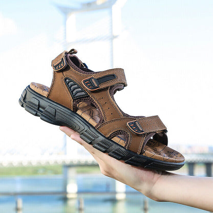 Hand holding Marlow brown sandal outdoors with bridge in background